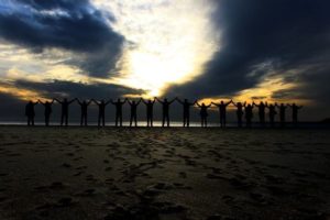 Hilera de personas alzando sus manos en la playa