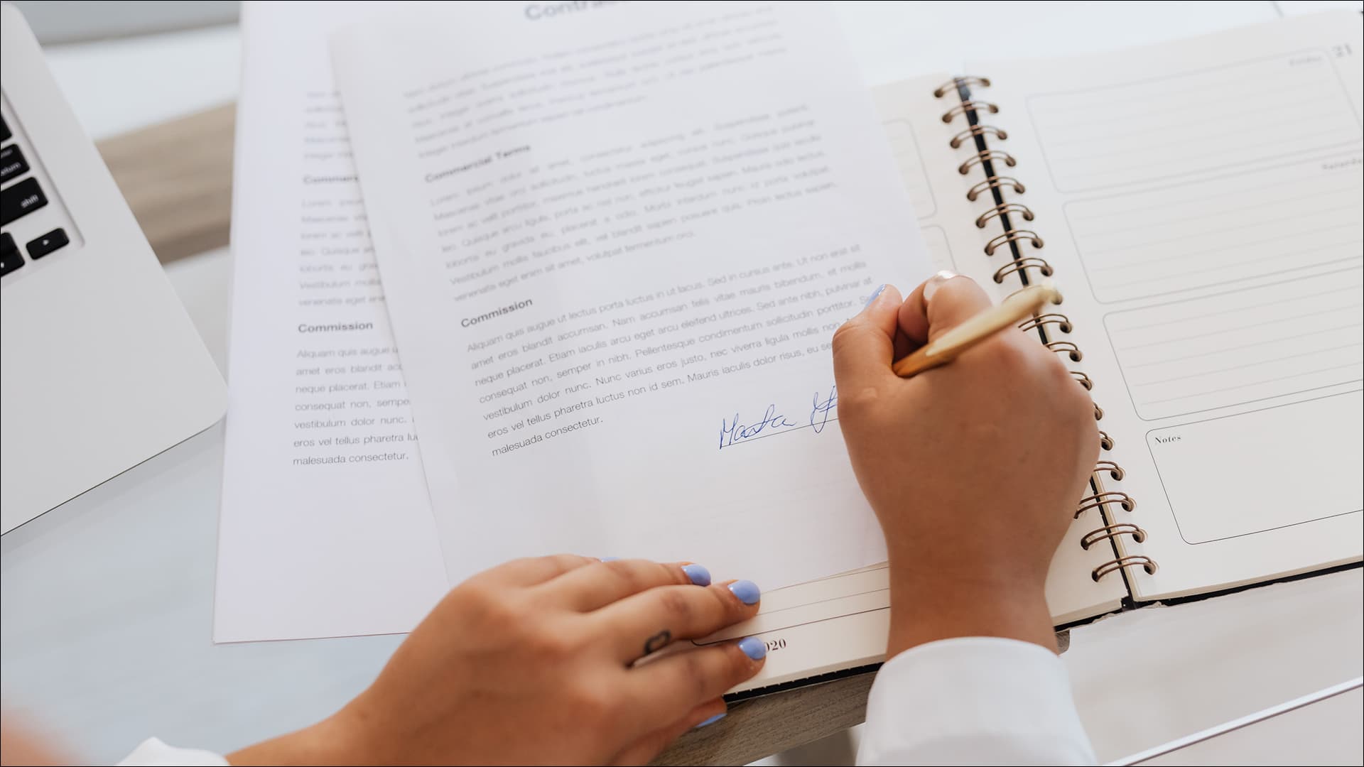 Primer plano de unas manos firmando un contrato sobre una mesa de oficina.