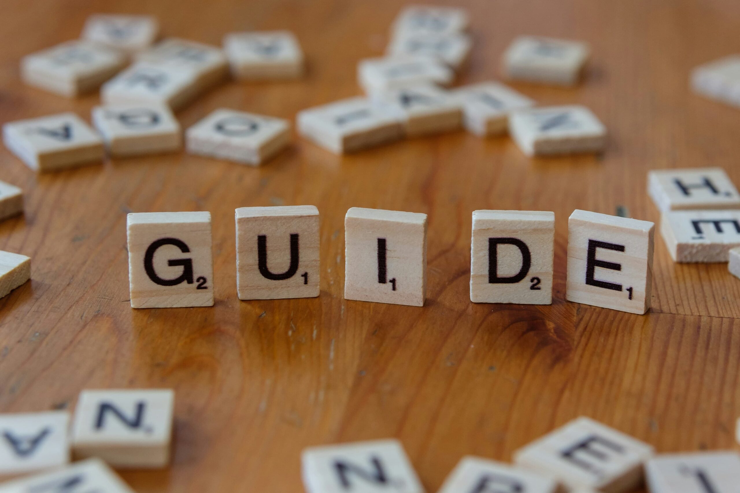 Fichas de madera formando la palabra GUIDE sobre una mesa para la guía de cómo crear una fundación.